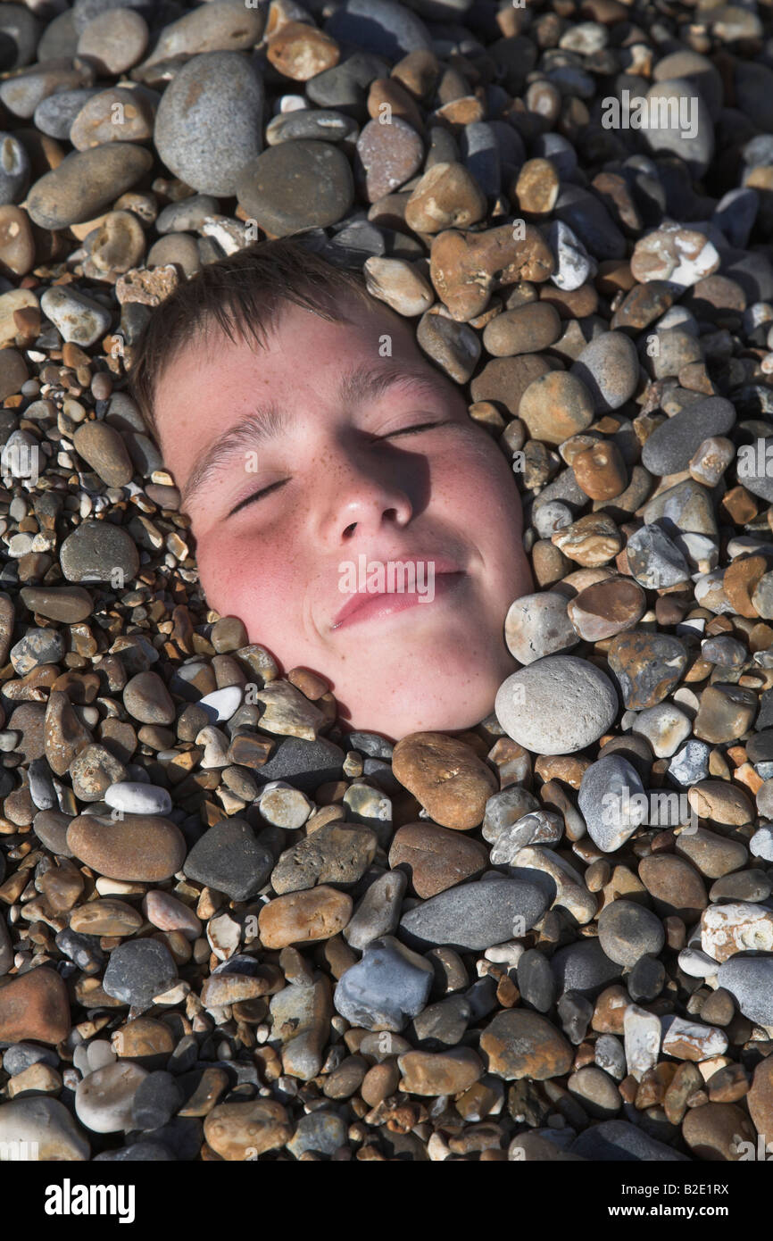 Boy's face buried in shingle beach Stock Photo Alamy
