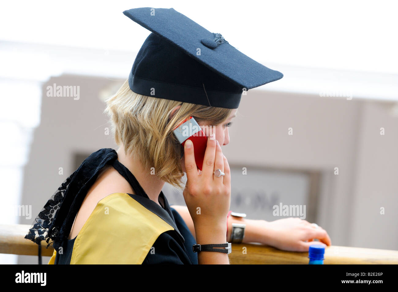 University of Sussex summer graduations at the Brighton Dome - a happy graduate on a mobile phone after the ceremony. Stock Photo