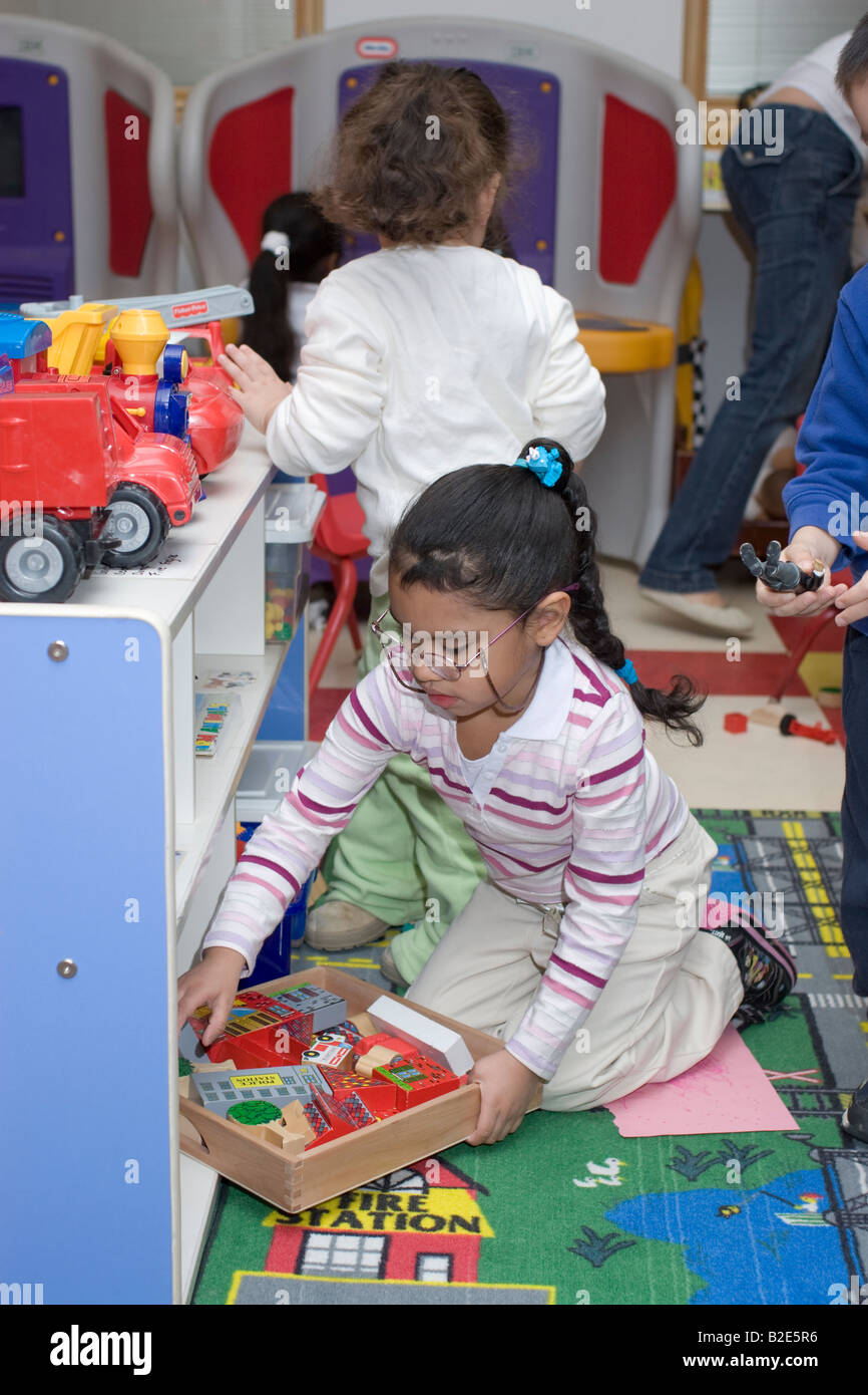 4 year old Filipino preschool girl putting toys away Stock Photo