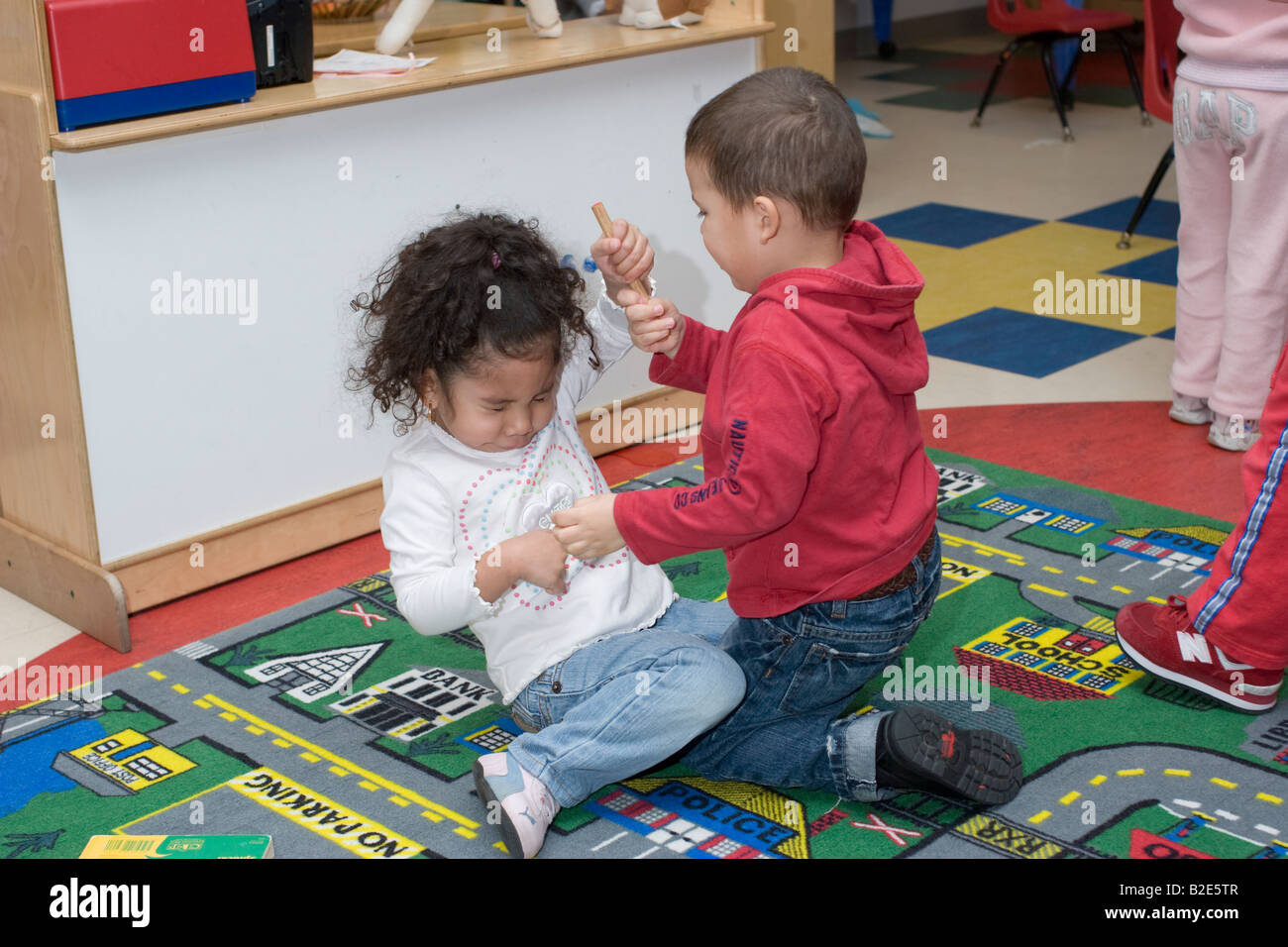 4 year old girl and boy fighting over a toy in school Stock Photo