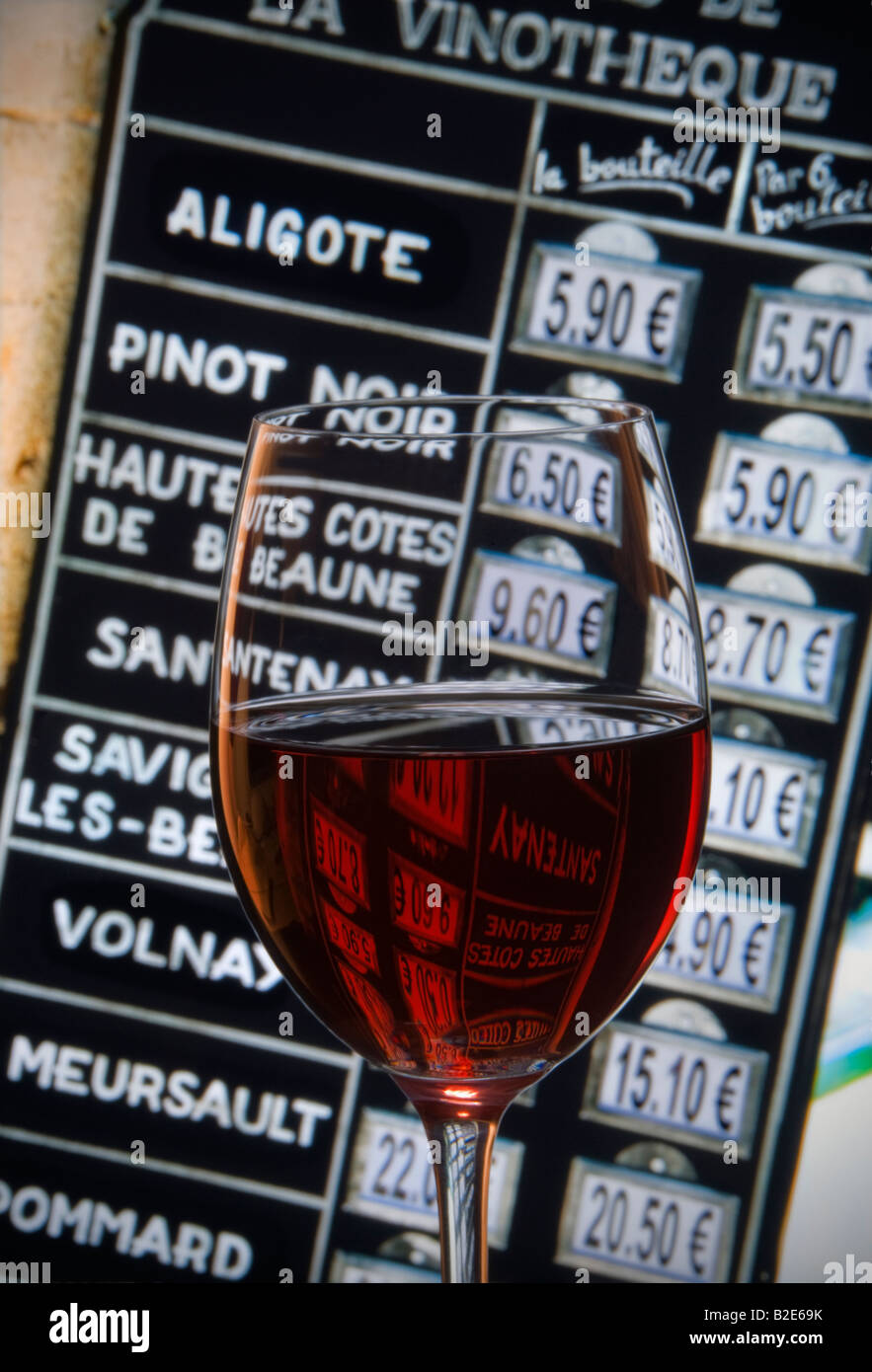 Glass of red wine in front of Burgundy wine shop euro price blackboard