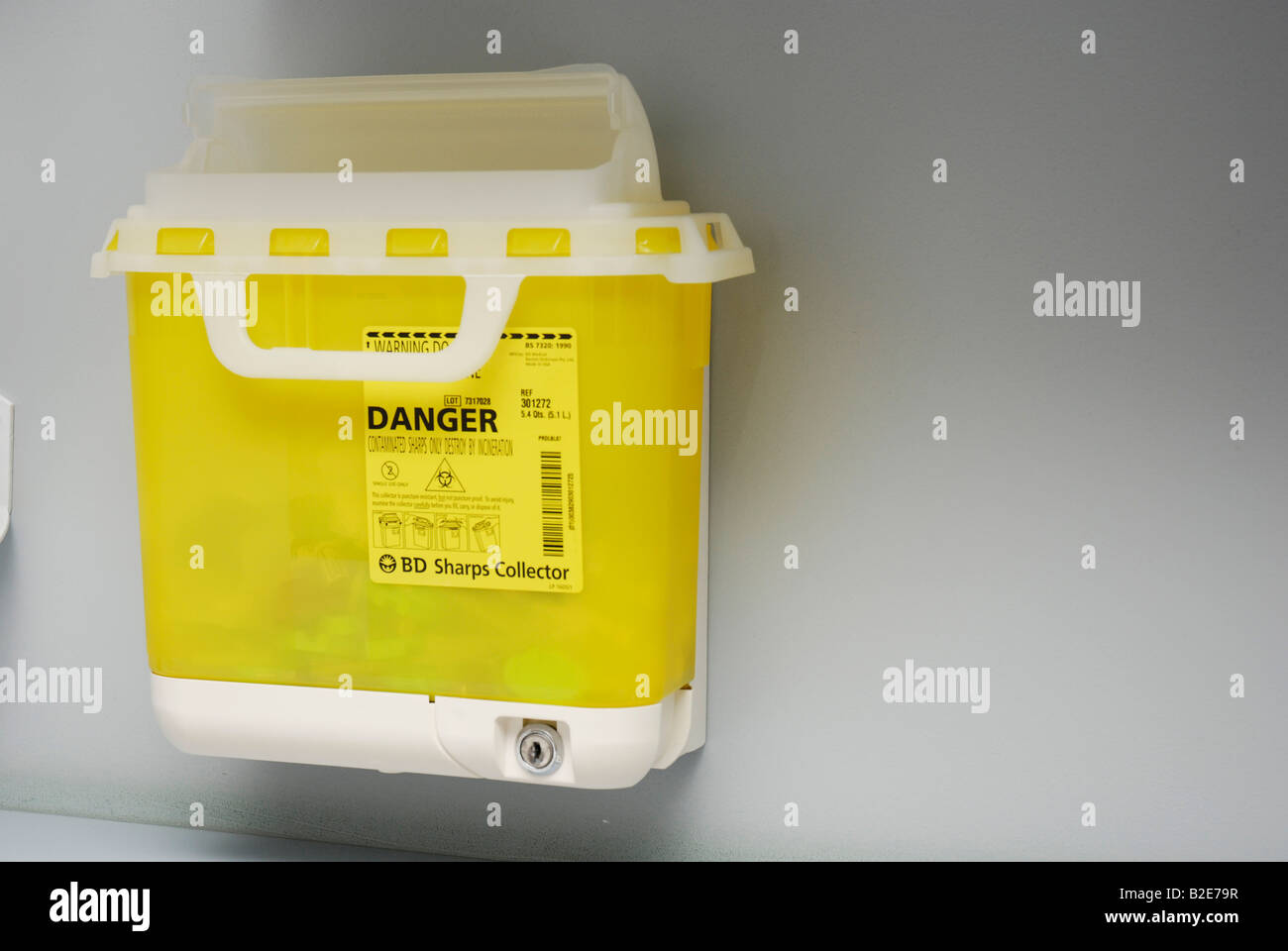 Sharps collector mounted on a wall for the disposal of syringes and other hazardous materials Stock Photo