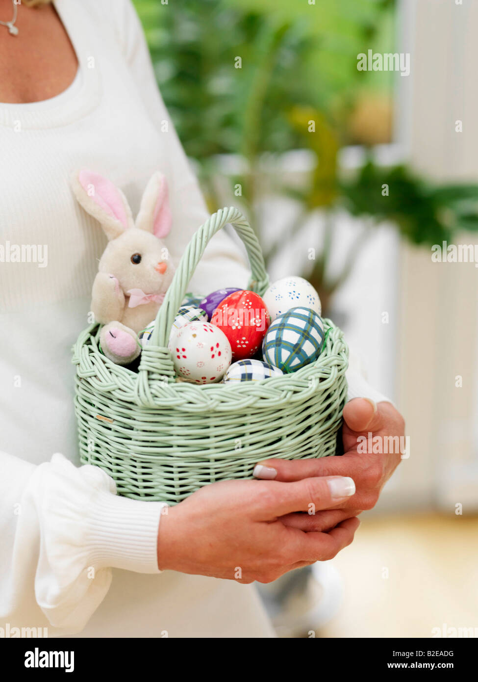 Mid section view of woman carrying basket of easter eggs Stock Photo
