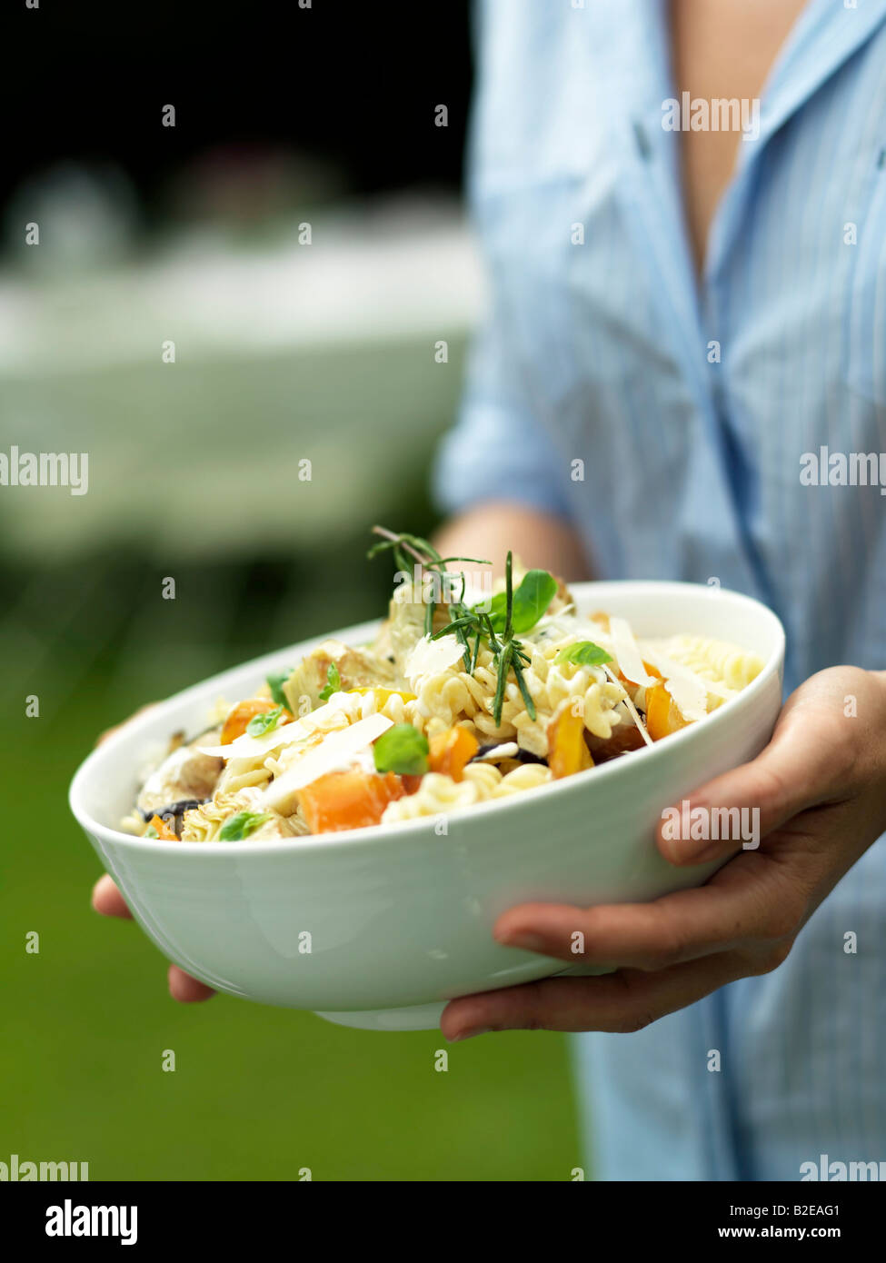 Mid section view of woman holding bowl of pasta salad Stock Photo