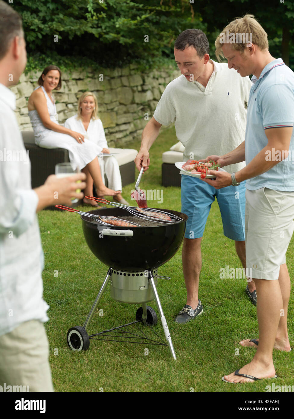 Two men preparing fish on barbeque grill in garden Stock Photo - Alamy