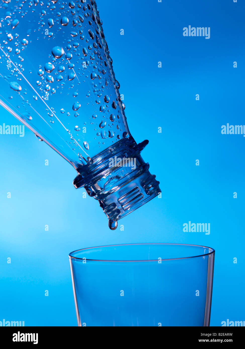 Close-up of water droplets being poured from bottle into glass Stock Photo