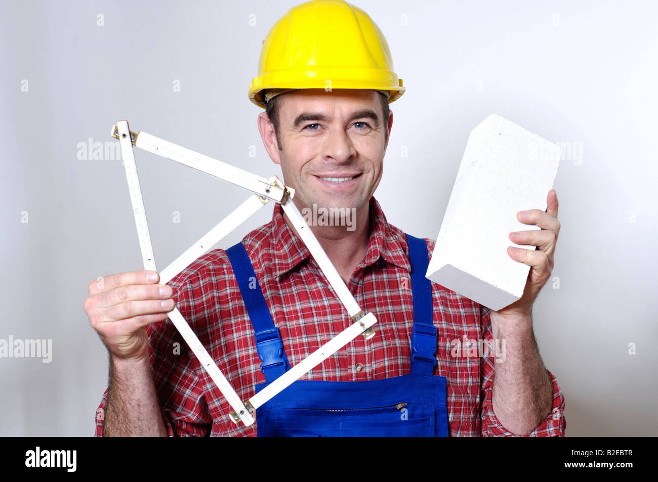 Portrait of man holding folding ruler and smiling Stock Photo