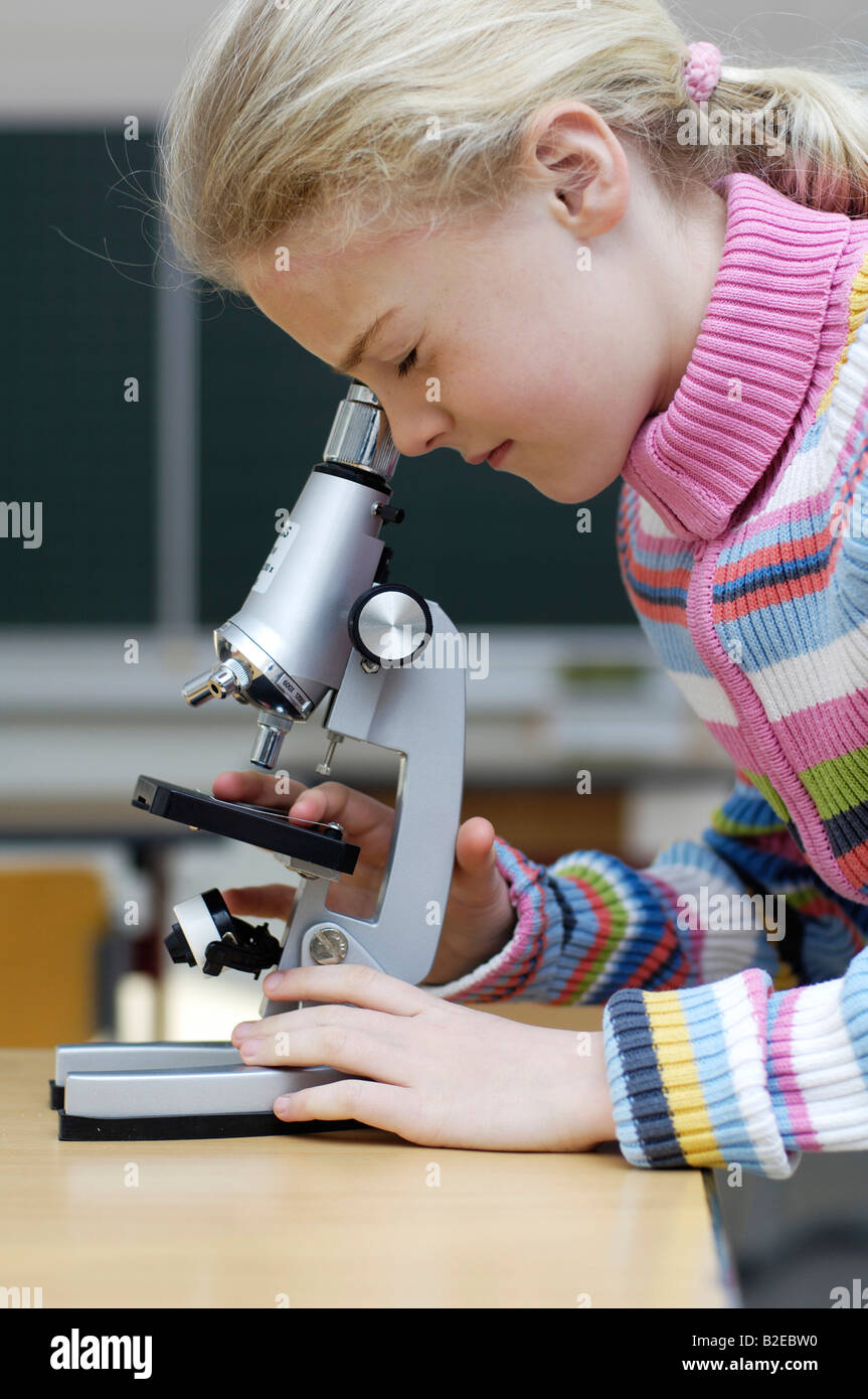 Side profile of girl looking through microscope Stock Photo