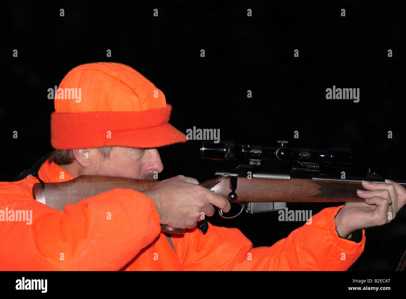 a deer hunter in hunter orange clothing holding a high powered rifle