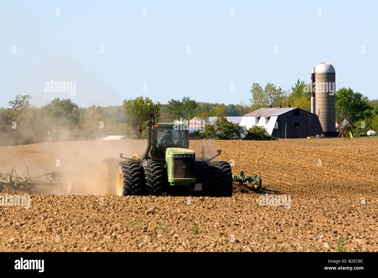 Large tractor cultivating spring soil on a farm in Lapeer County Michigan Stock Photo