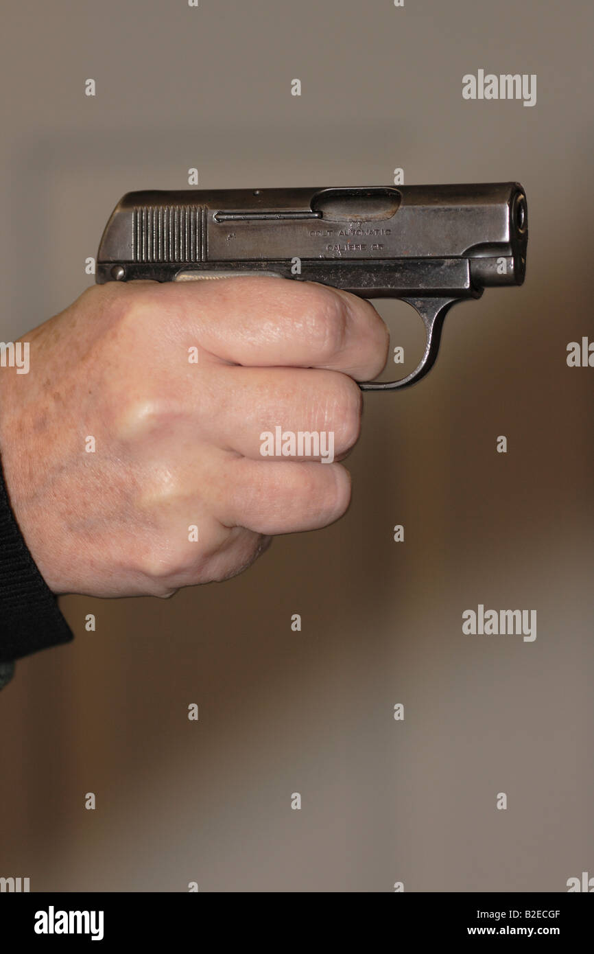 a small semi-automatic pistol held in a hand and pointed Stock Photo