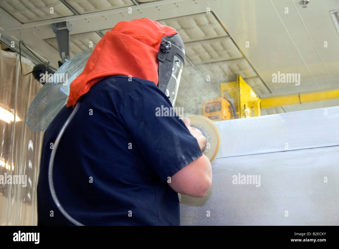 Worker wearing protective safety gear while using a power sander on