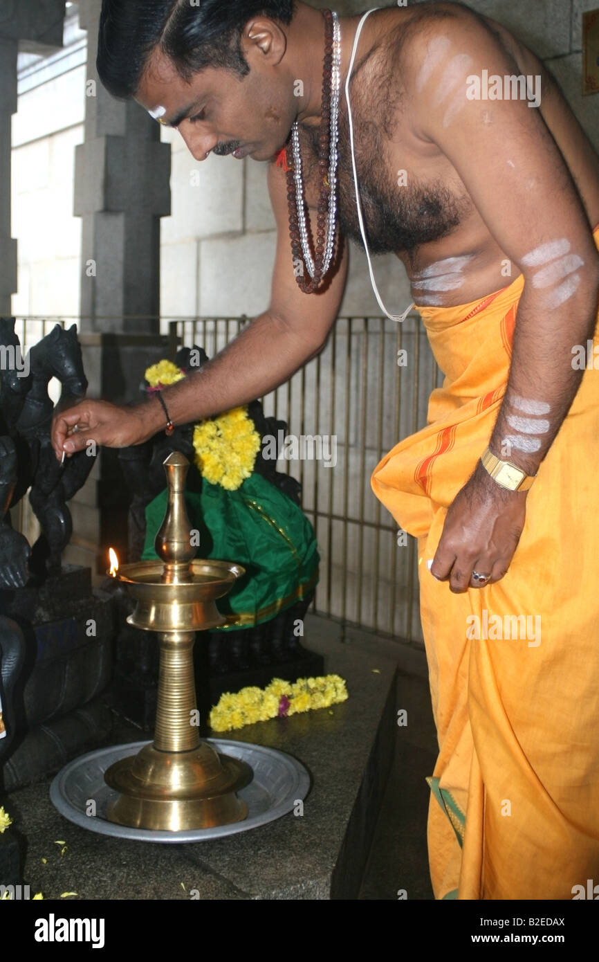 Hindu priest lights an oil lamp or diva as part of his morning temple