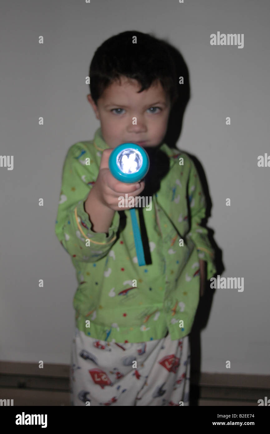 a 5 yr old boy in pajamas with a flashlight searching in the dark Stock Photo