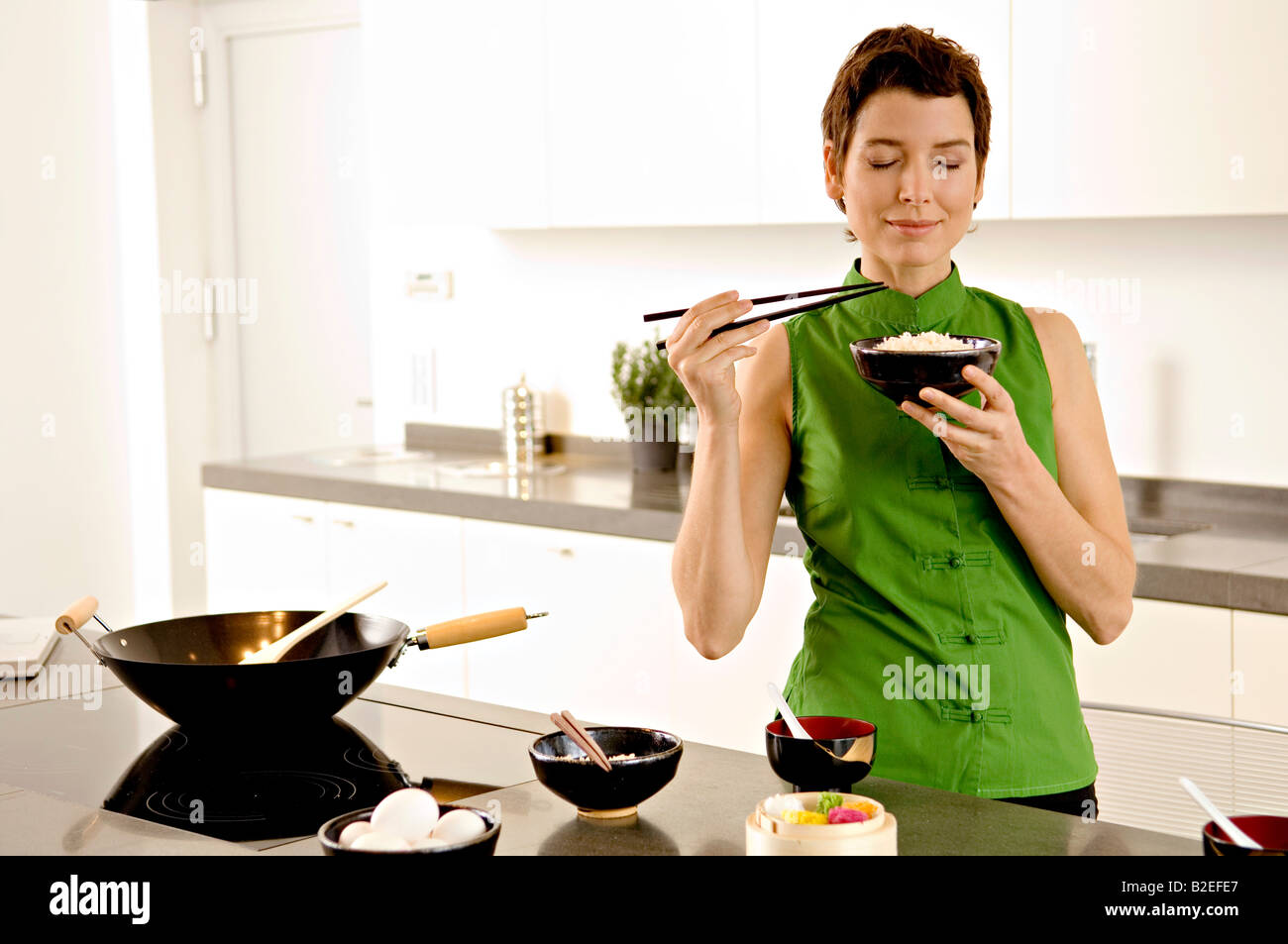 Mid adult woman smelling a bowl of rice in the kitchen Stock Photo Alamy