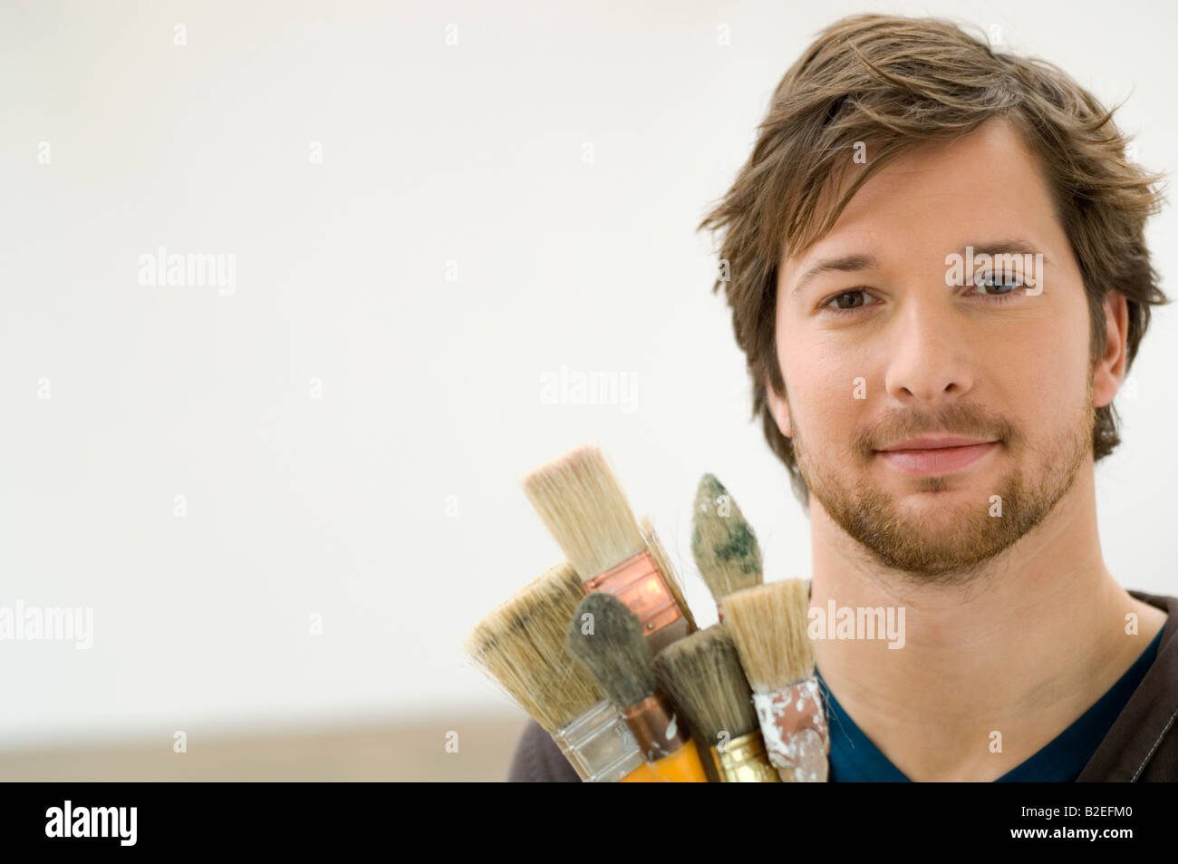 Portrait of a mid adult man holding paintbrushes Stock Photo
