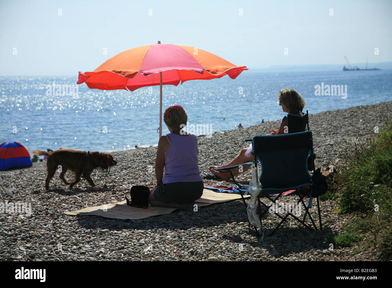 Two people sitting under a sun umbrella Stock Photo