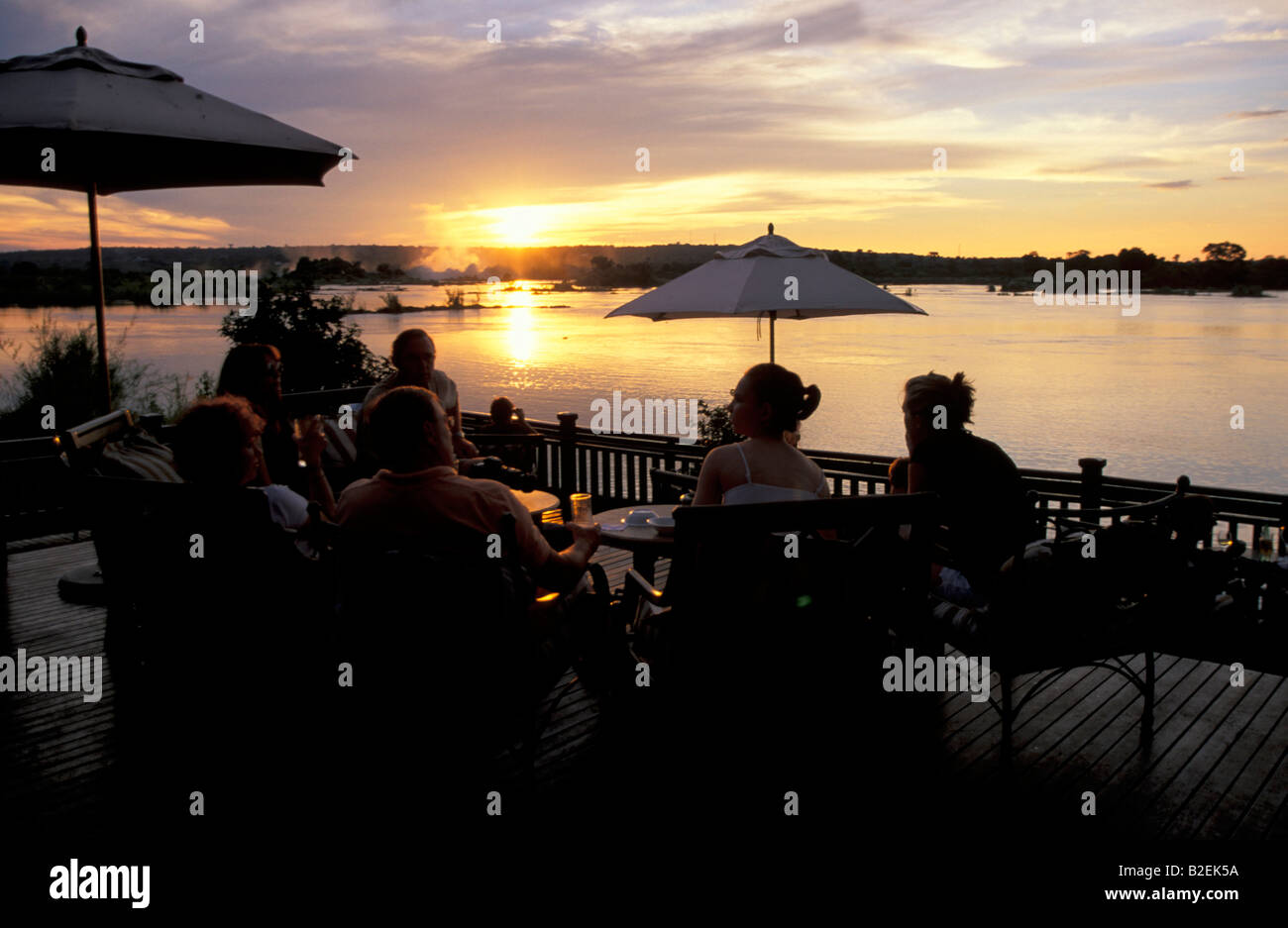Tourists having sundowners drinks at Royal Livingstone hotel on the banks of the Zambezi river looking out to Victoria Falls Stock Photo