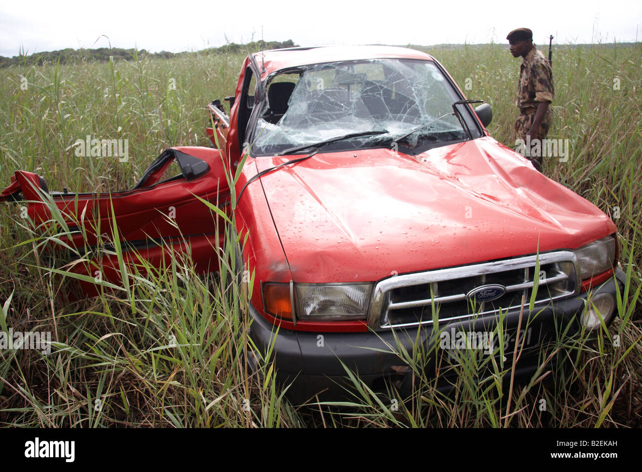 Ranger looking at a vehicle damaged by an Elephant attack Stock Photo