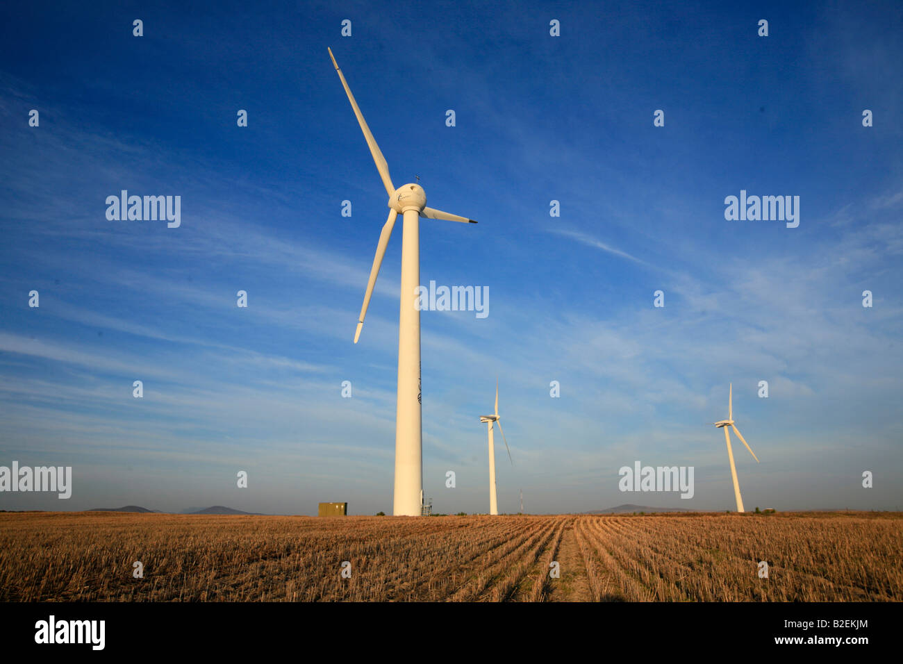 Wind Turbines against a blue sky streaked with cloud Stock Photo