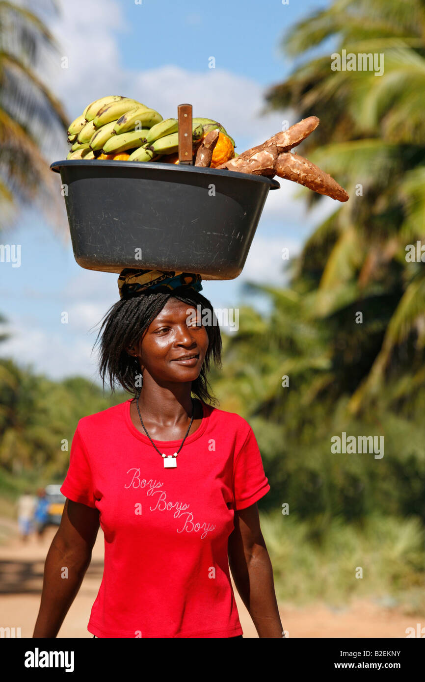 A woman balancing a black plastic bowl on her head with bananas and sweet  potato and for sale to locals Stock Photo - Alamy