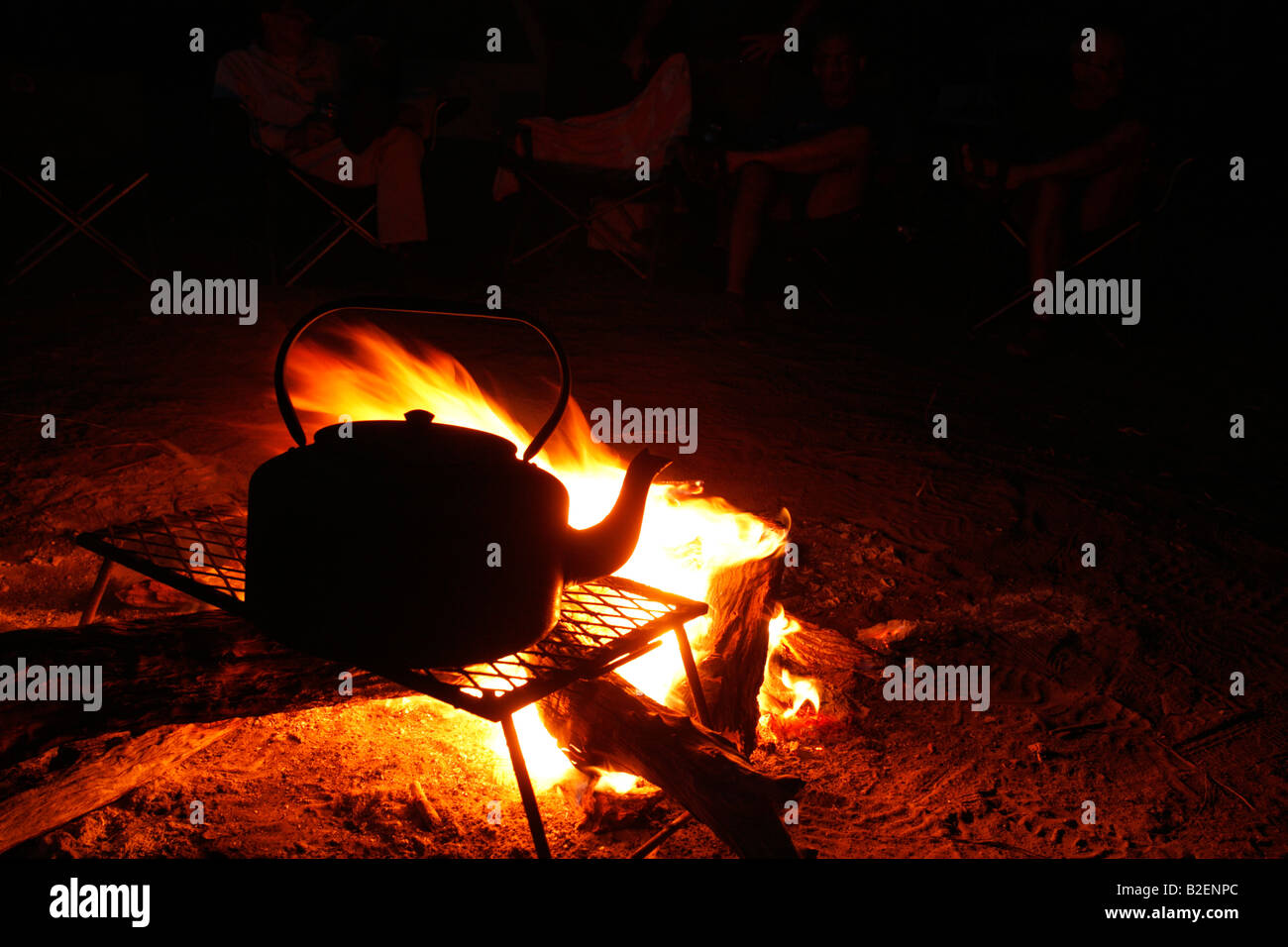 Wide angle view of a blazing log fire with a kettle in a campsite at night Stock Photo
