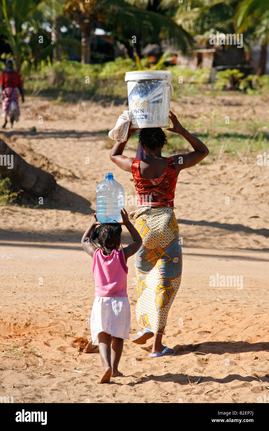 A local woman and her daughter carry water in buckets balanced on their heads Stock Photo