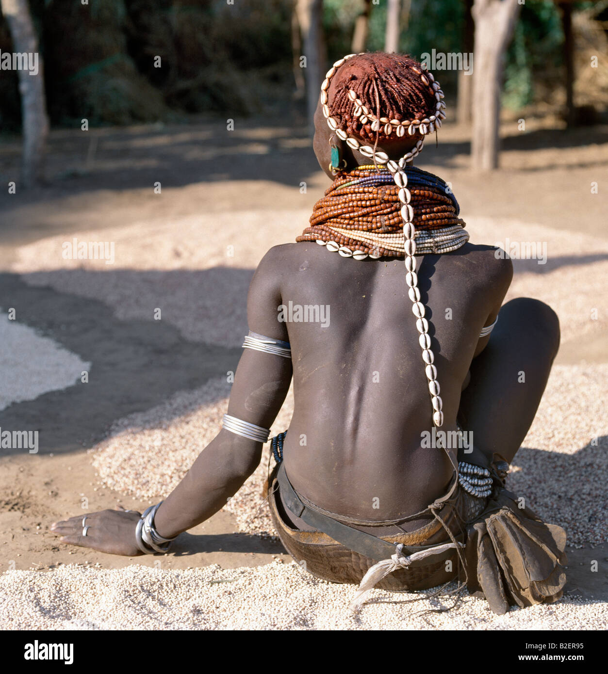 A Nyag'atom woman dries sorghum and other corn at her homestead near the banks of the Omo River. Stock Photo