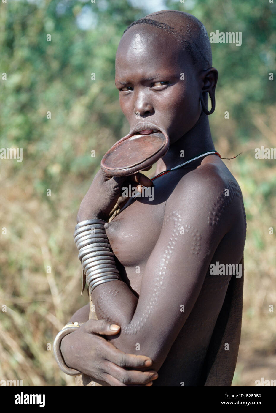 A Mursi woman with attractive scarification wears a large clay lip plate. Stock Photo