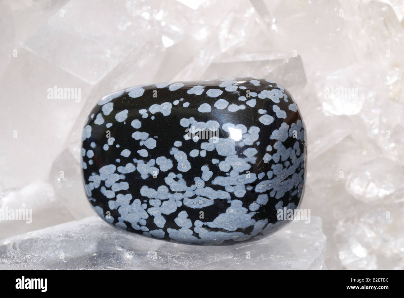Flake obsidian gem energized on druze of quartz crystals. This gem is used as a jewel stone and also in alternative medicine. Stock Photo