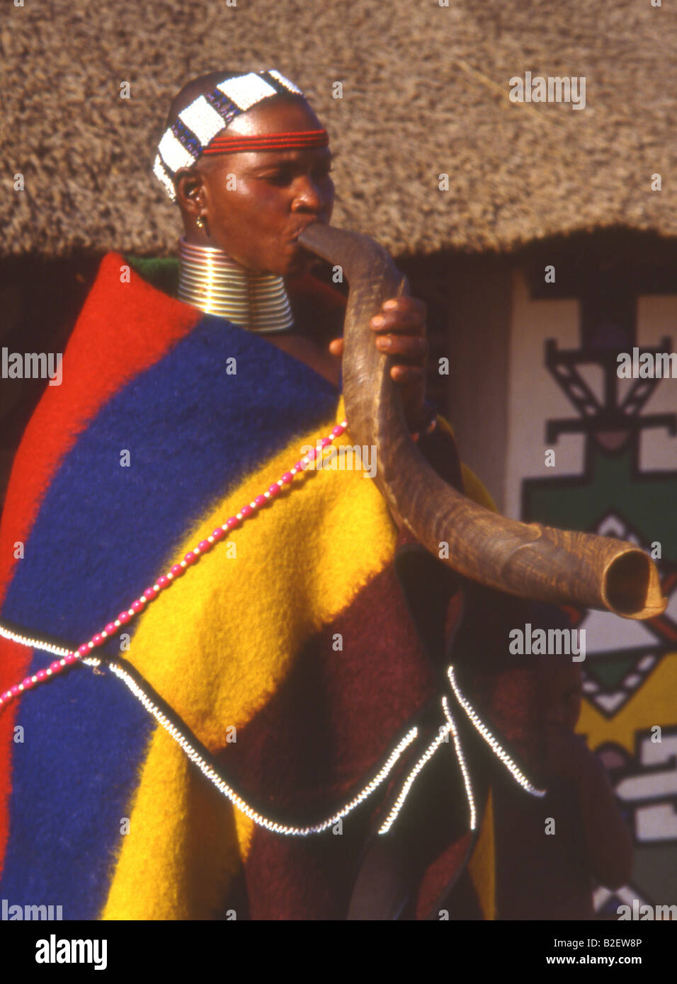 Ndebele Woman in traditional dress blowing on Kudu horn Stock Photo
