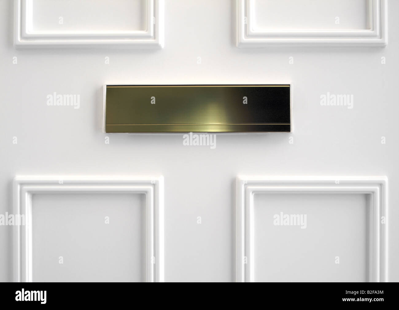 Brass letter box on the inside of white paneled upvc front door Stock Photo