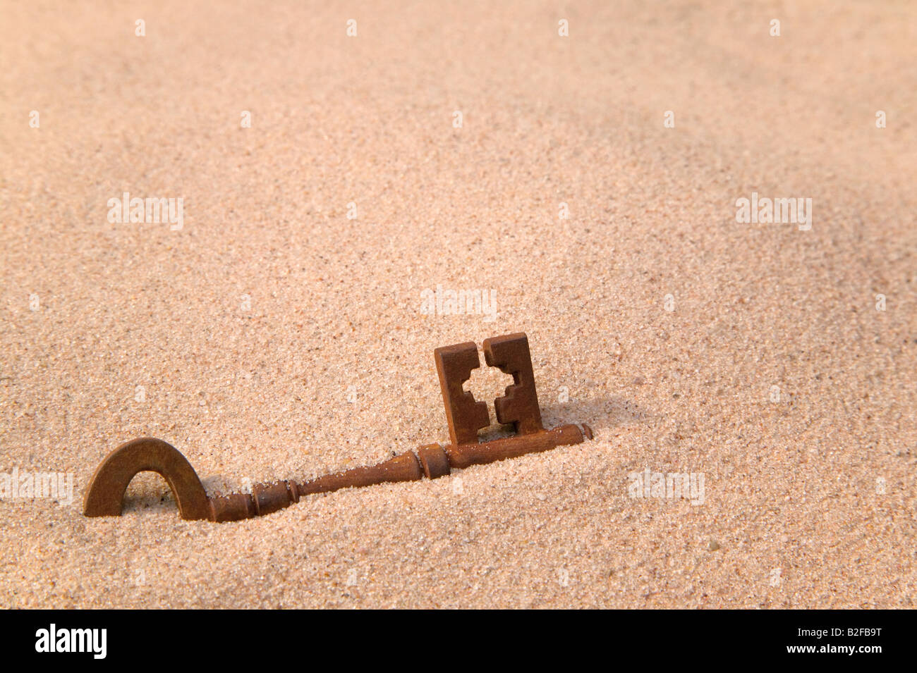 A rusty old key part buried in sand Stock Photo - Alamy