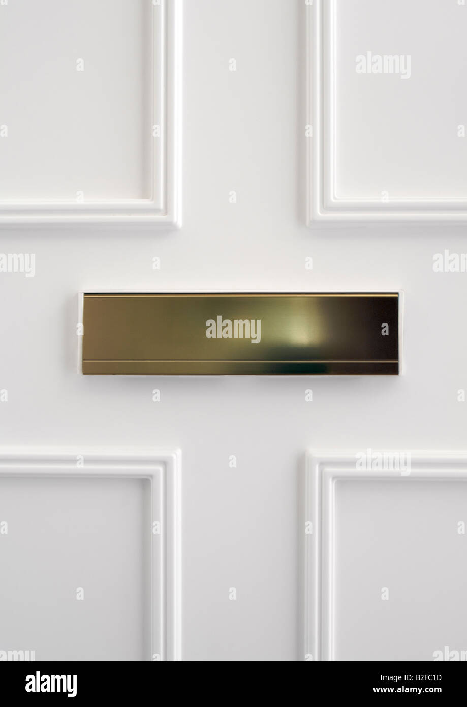 Brass letter box on the inside of white paneled upvc front door Stock Photo