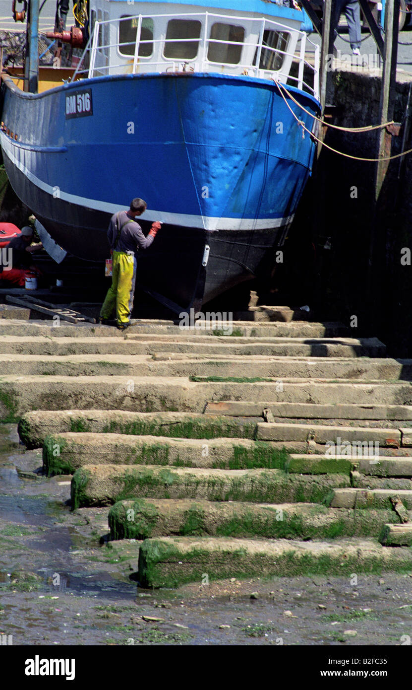 Man painting a boat in Brixham harbour Devon England Stock Photo