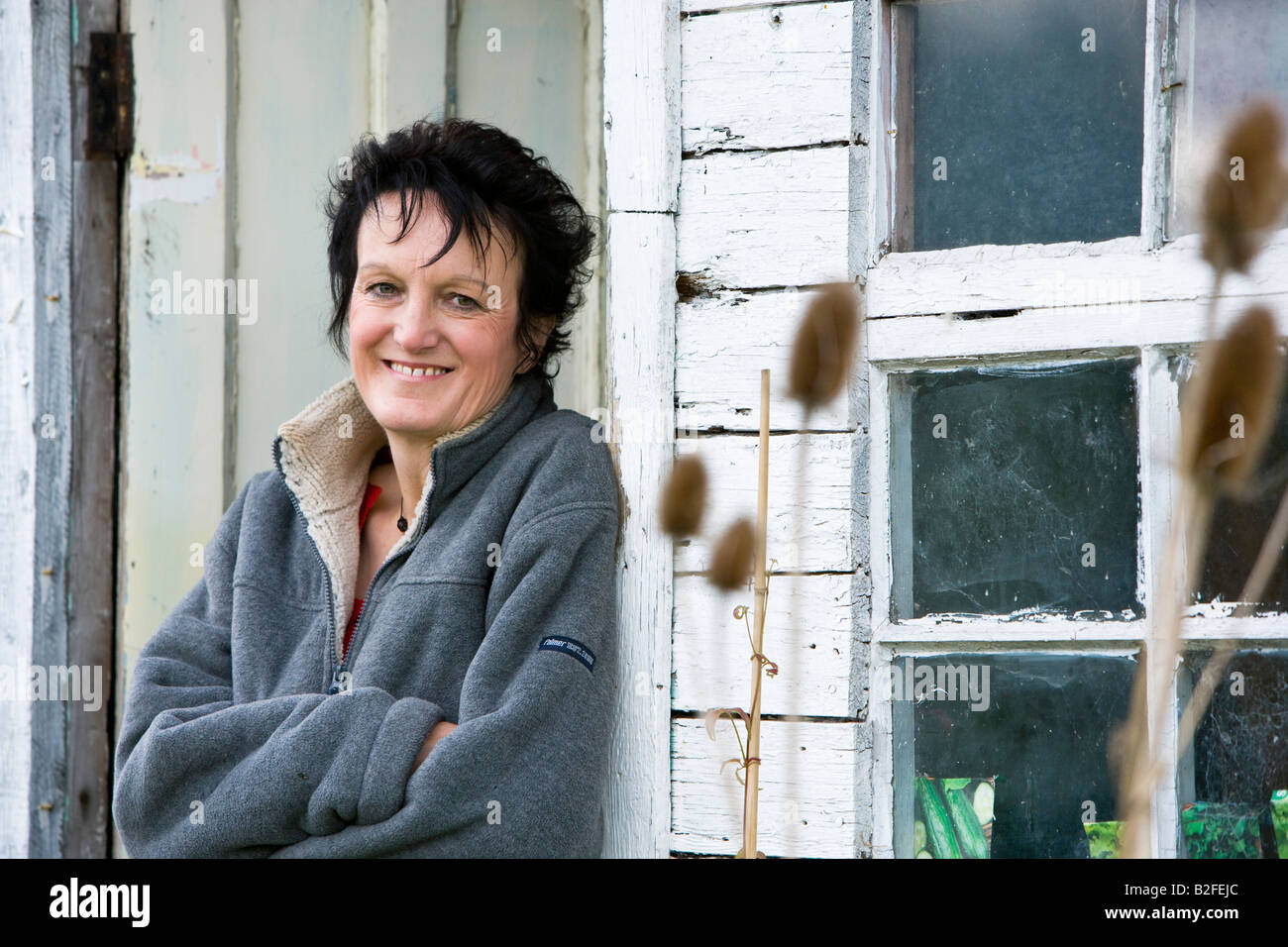 lady sat outside her garden shed Stock Photo