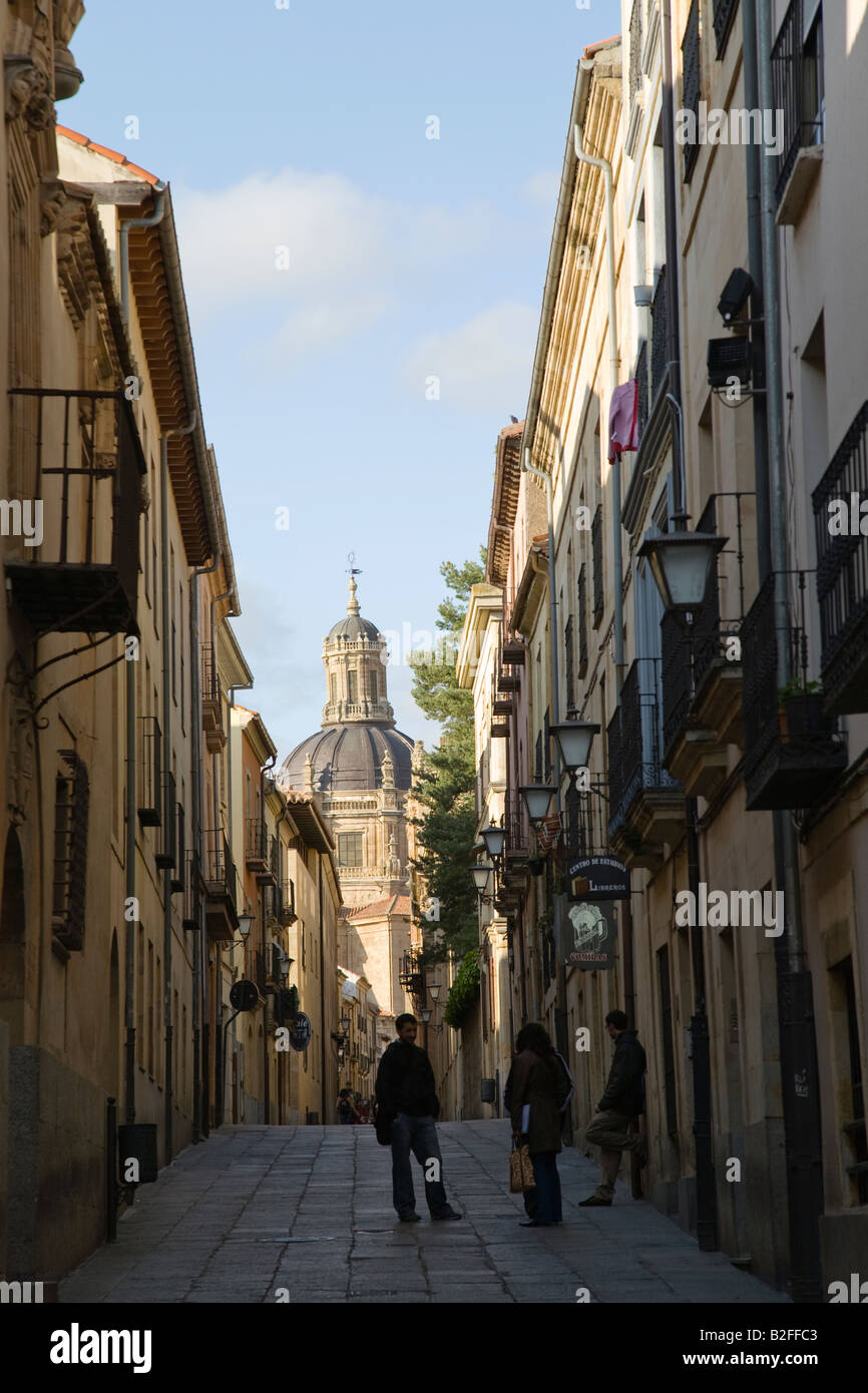 SPAIN Salamanca Dome of Pontificia University viewed down narrow side street of city people talk together on sidewalk Stock Photo