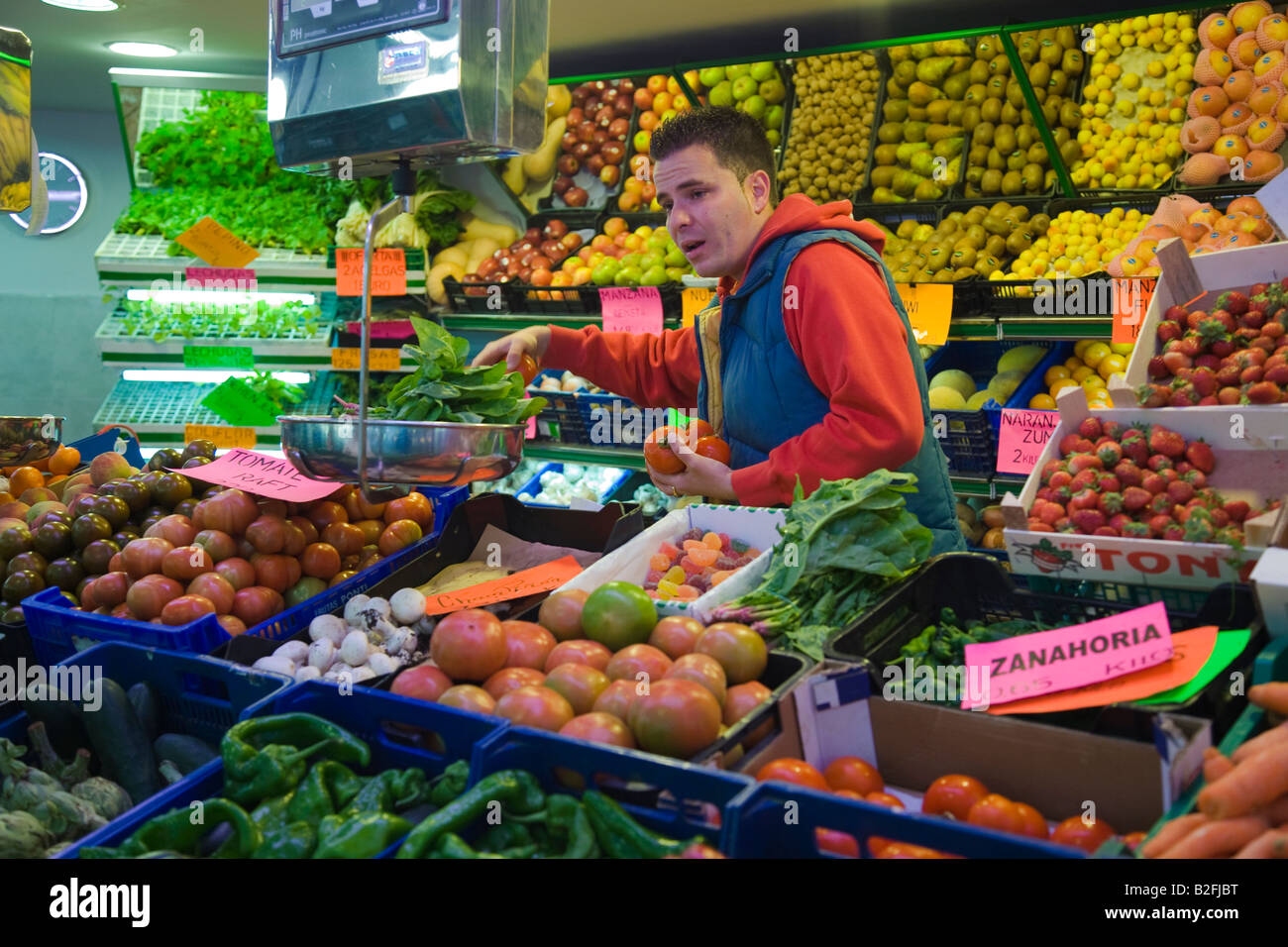 SPAIN Salamanca Man select fresh produce for customer at fruit and vegetable booth in indoor market Stock Photo