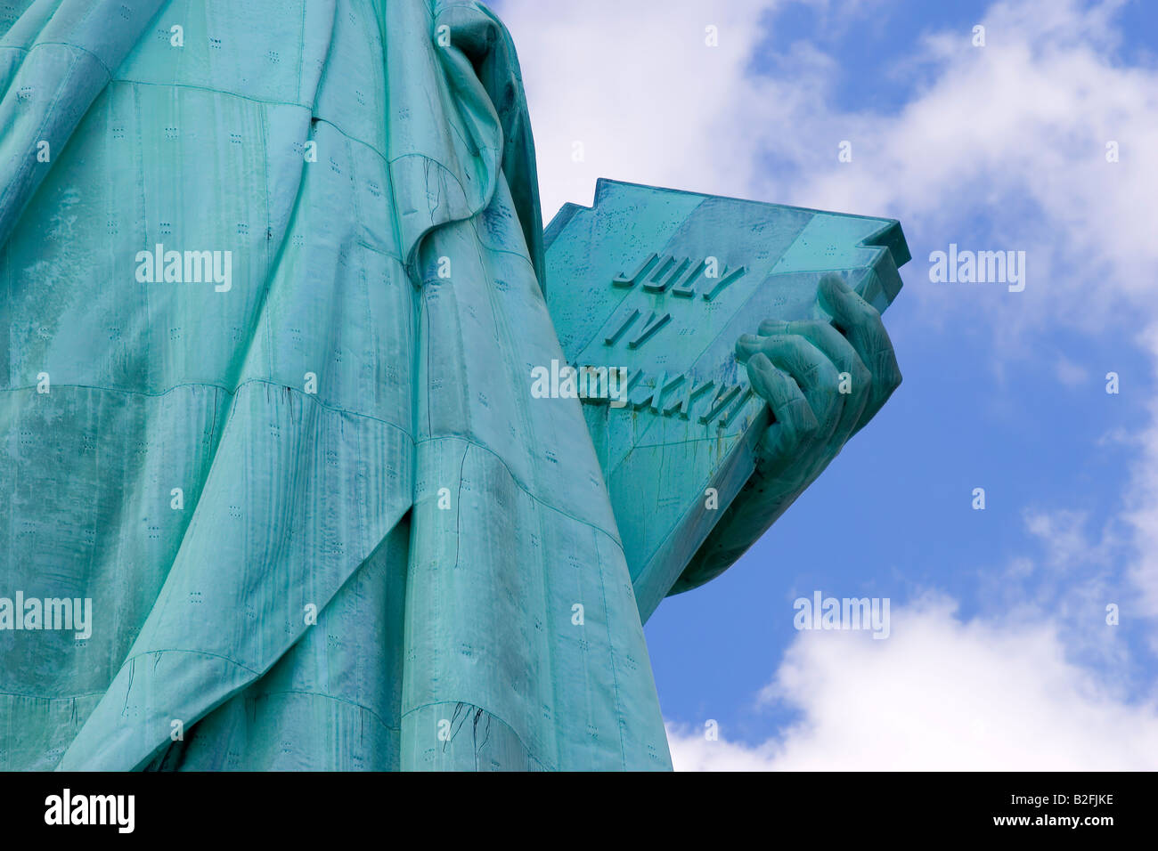 Statue of liberty close up on arm holding book on clear blue day Stock