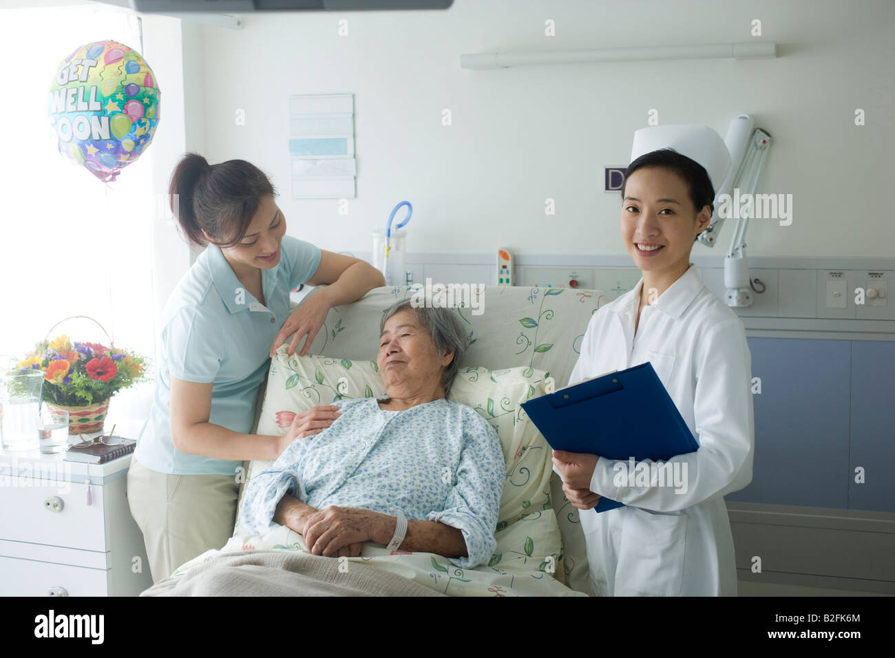 Portrait of a female nurse holding a clipboard with a patient and her ...