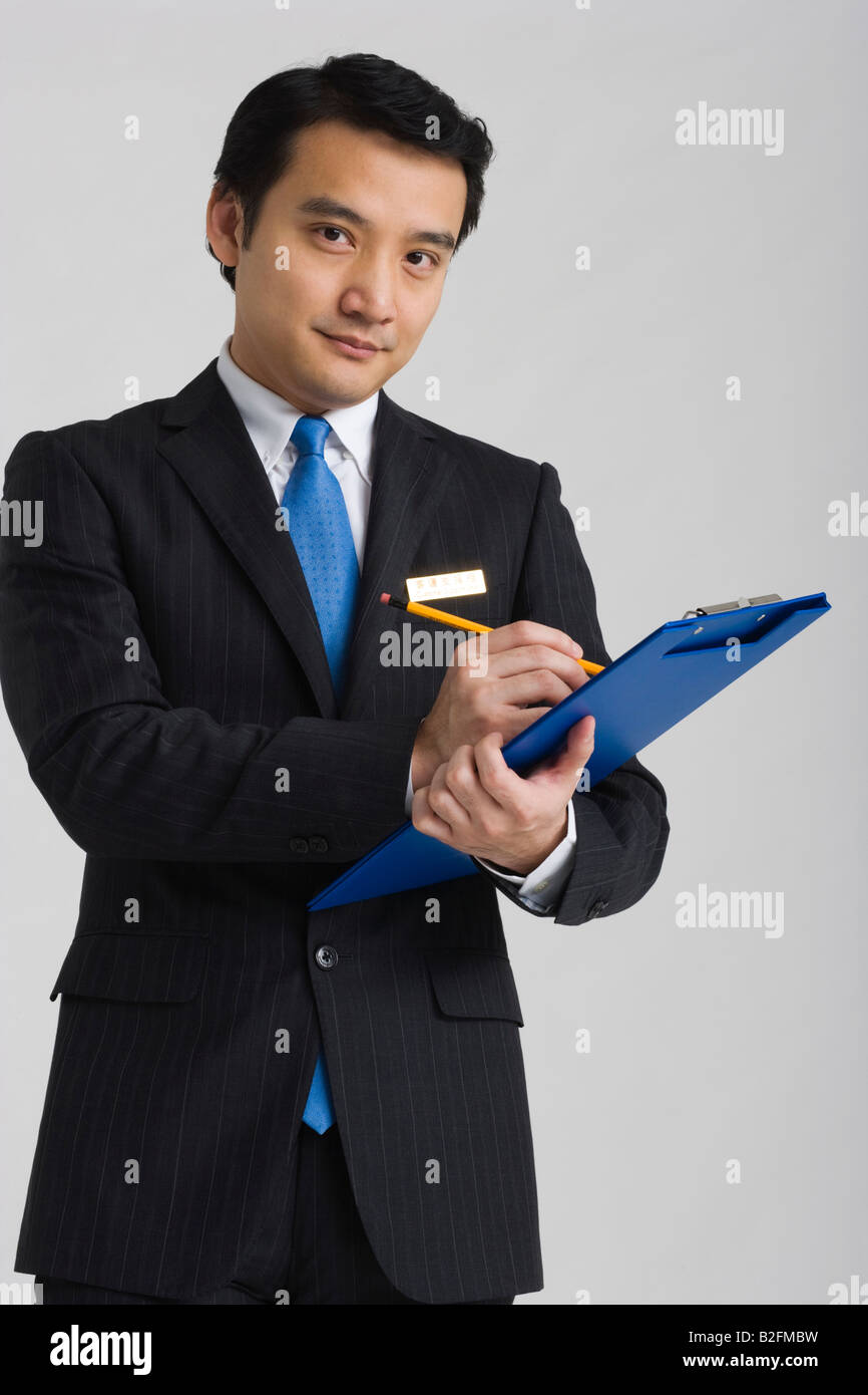 Portrait of a businessman holding a pencil and a clipboard Stock Photo ...