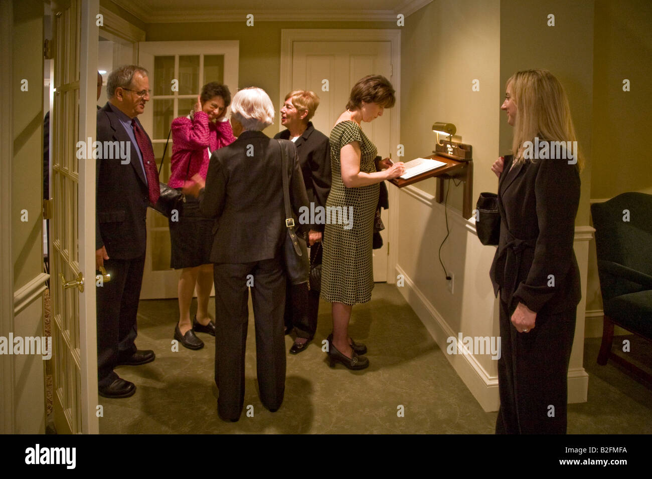 Guest arriving for a Catholic funeral in Stoneham MA are greeted by the deceased s daughter Note woman signing guest register Stock Photo