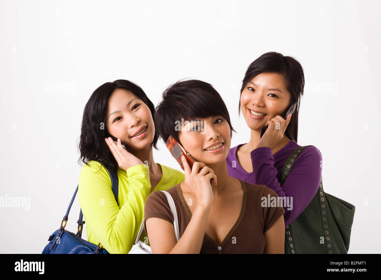 Three young women talking on mobile phones and smiling Stock Photo - Alamy
