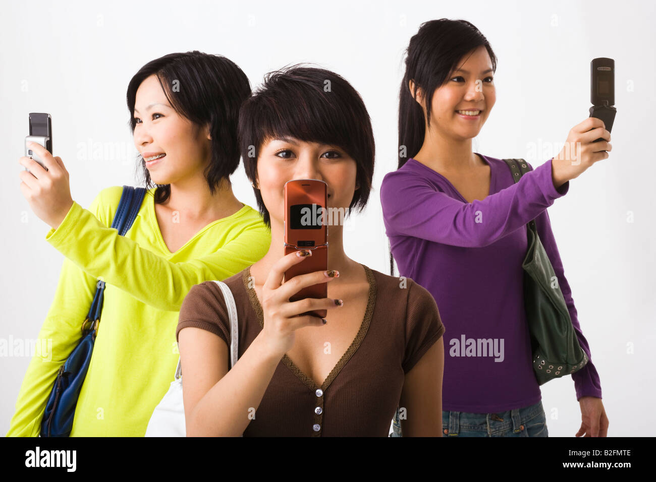 Three young women using mobile phones Stock Photo - Alamy