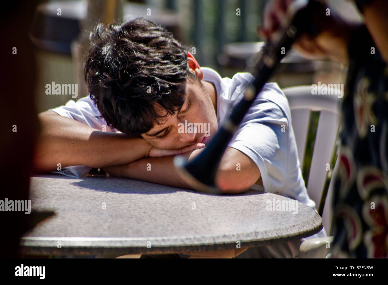 A young Hispanic man listens intently to Le Jazz Hot music at outdoor band performsnce in Coronado CA Note clarinet foreground Stock Photo