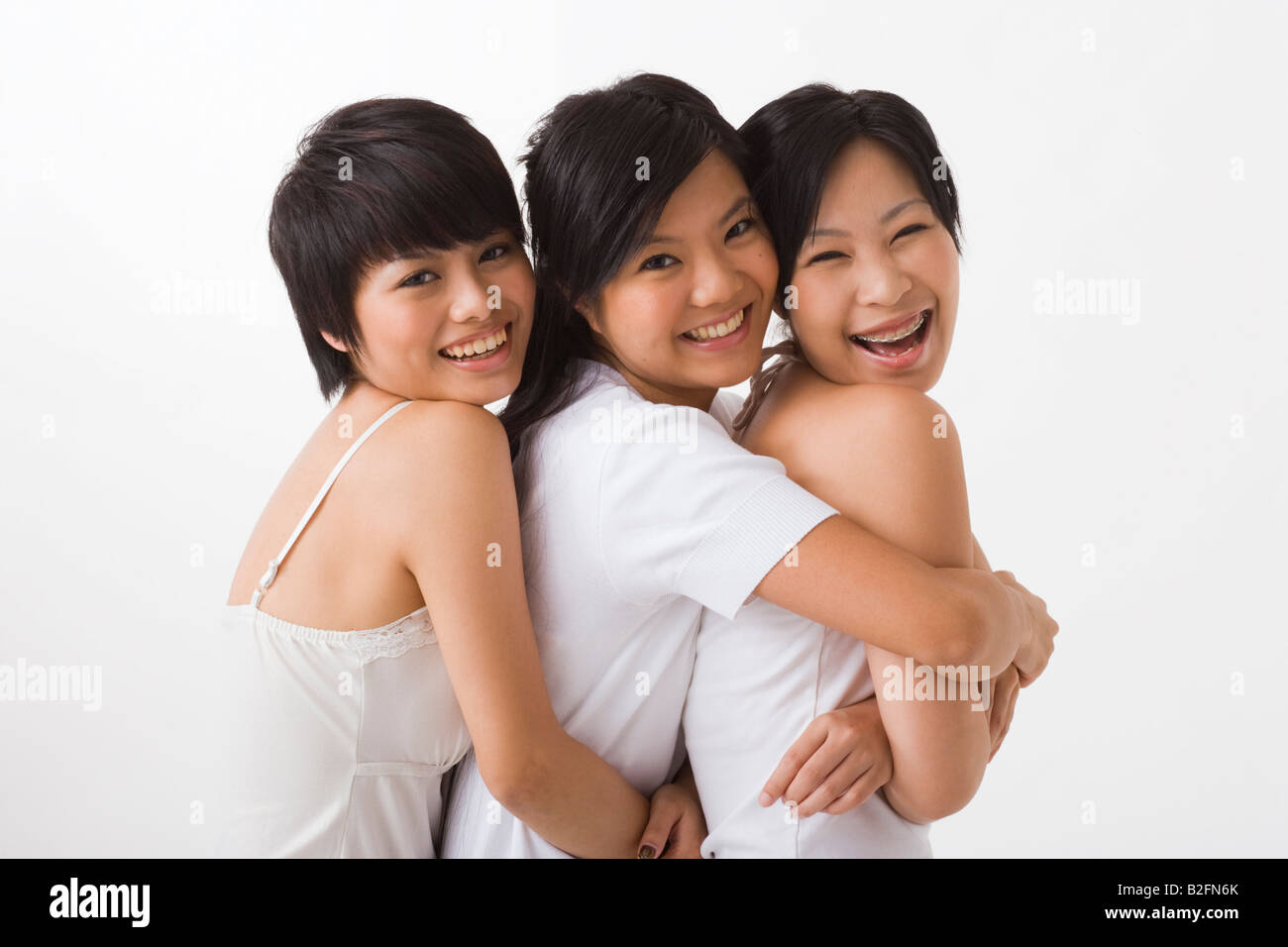 Portrait of three young women standing together and smiling Stock Photo ...