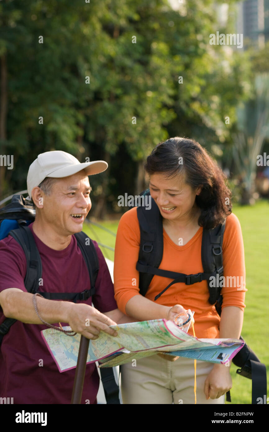 Close-up of a mature man holding a map with a mature woman holding a compass and smiling Stock Photo