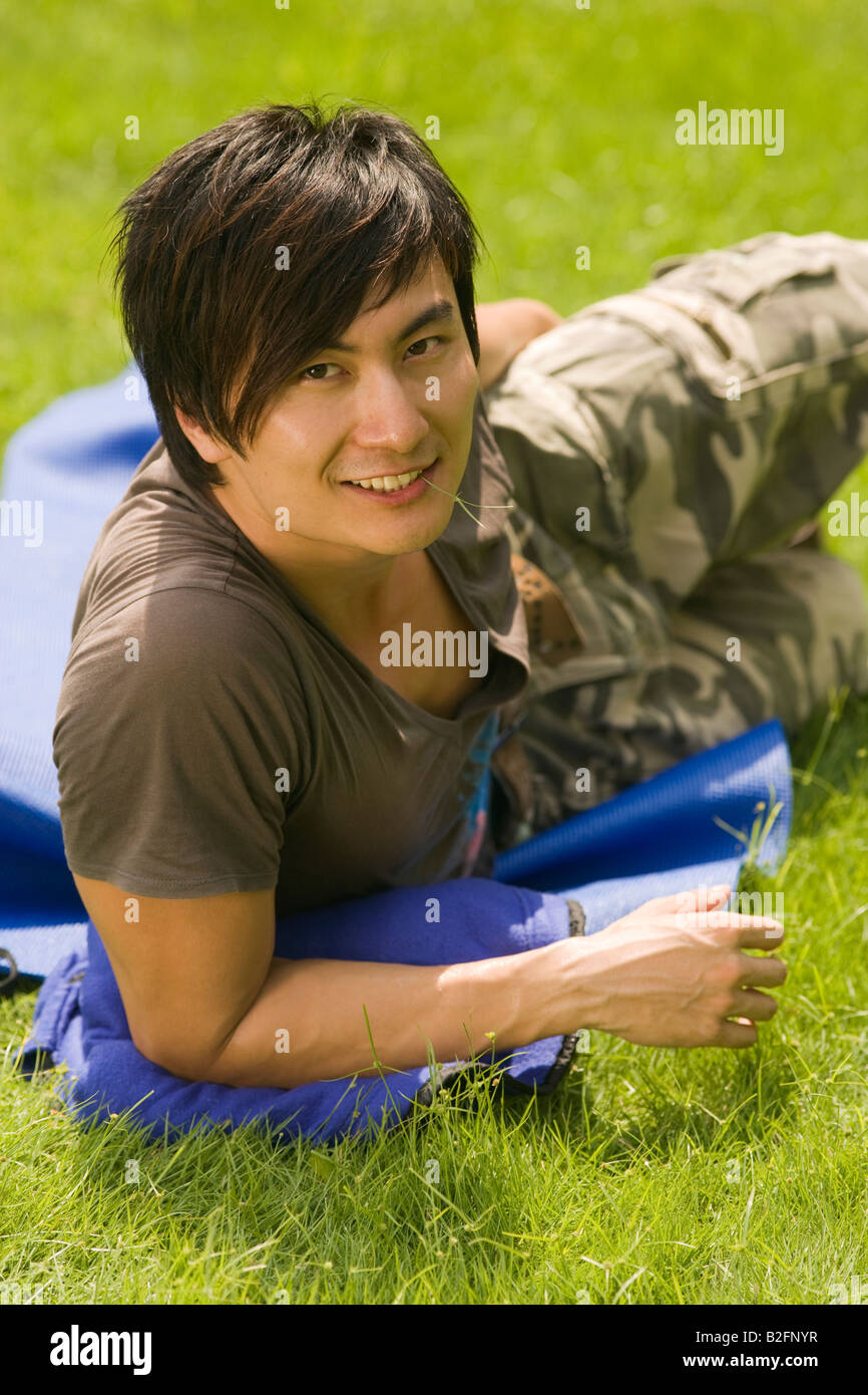 Portrait of a young man lying in a park and smiling Stock Photo - Alamy