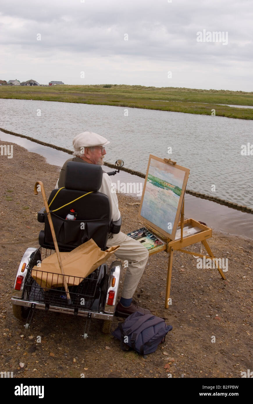 An elderly man on a mobility scooter  Painting A Landscape At Walberswick,Suffolk,Uk Stock Photo
