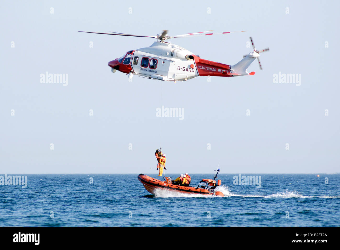 A co ordinated operation with the In shore lifeboat and Coastguard helicopter winching a man out of the English channel Stock Photo